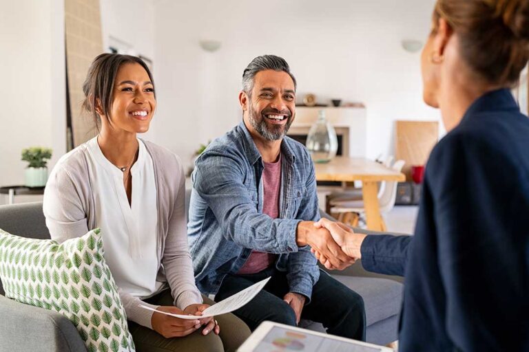 A couple and a real estate agent review documents and exchange a check during a home buying meeting.